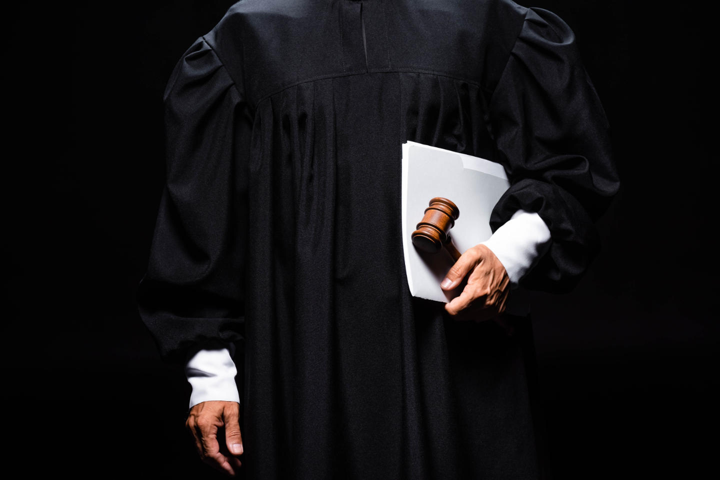 Cropped view of judge in judicial robe holding gavel and papers